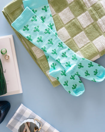 Blue cactus socks on green checkered towel